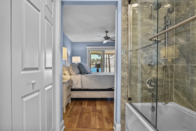 bathroom featuring a ceiling fan, ensuite bathroom, a textured ceiling, wood finished floors, and combined bath / shower with glass door