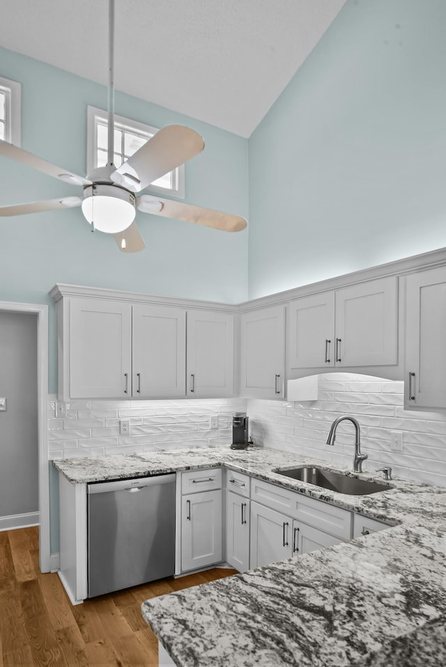 kitchen featuring high vaulted ceiling, a sink, light stone counters, stainless steel dishwasher, and ceiling fan