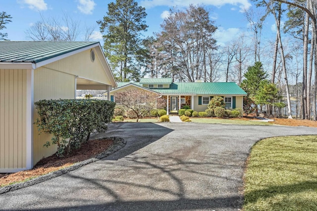 view of front of house featuring metal roof, a carport, driveway, and a standing seam roof