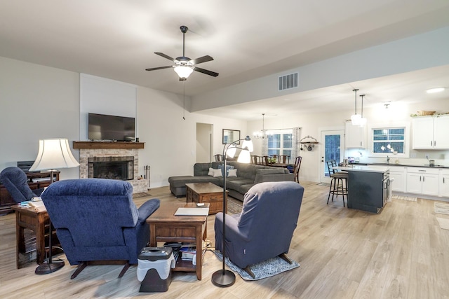 5761 Dixie Hwy, Rutledge, GA 30663 - living room featuring a ceiling fan, light wood finished floors, a fireplace, and a chandelier