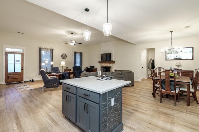 5761 Dixie Hwy, Rutledge, GA 30663 - kitchen featuring a stone fireplace, light wood finished floors, a chandelier, light countertops, and a ceiling fan