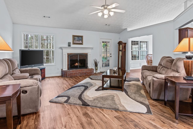 living area featuring a wealth of natural light, visible vents, wood finished floors, and a ceiling fan