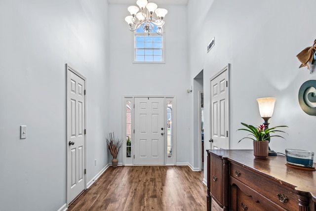 foyer entrance featuring an inviting chandelier, a high ceiling, baseboards, and dark wood-style flooring