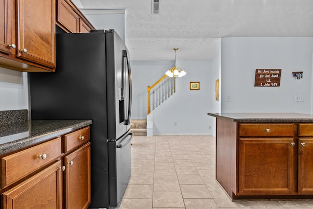 kitchen with dark countertops, brown cabinets, a textured ceiling, and light tile patterned flooring