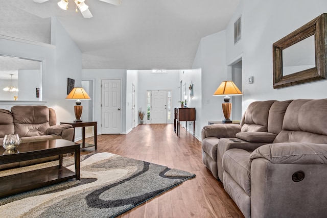 living area with visible vents, baseboards, hardwood / wood-style floors, ceiling fan with notable chandelier, and high vaulted ceiling