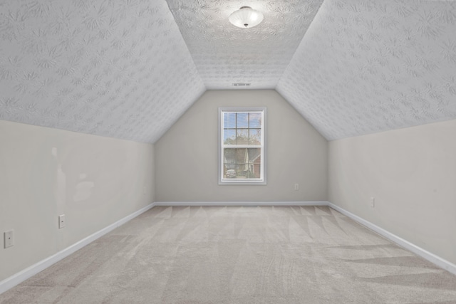 additional living space with baseboards, a textured ceiling, carpet flooring, and vaulted ceiling