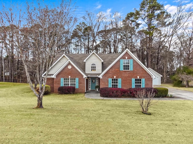 traditional home featuring brick siding, roof with shingles, concrete driveway, and a front yard