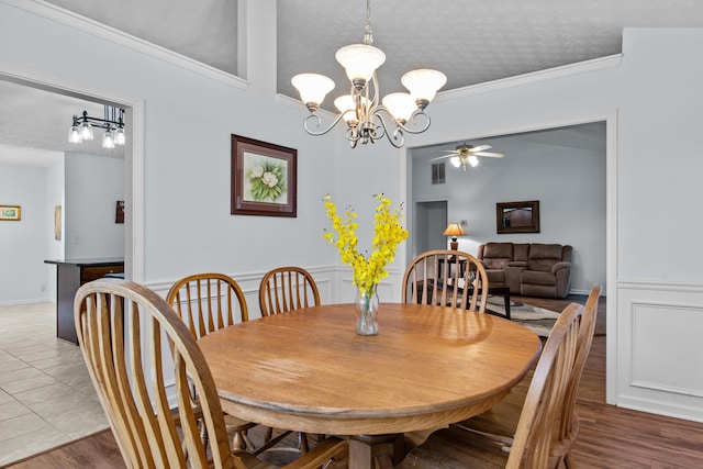 dining space with a textured ceiling, wood finished floors, crown molding, and ceiling fan with notable chandelier