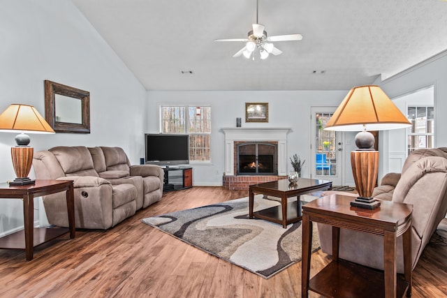 living area with a wealth of natural light, wood finished floors, a ceiling fan, and vaulted ceiling