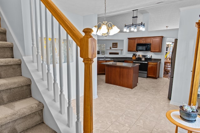 kitchen featuring dark countertops, a kitchen island, appliances with stainless steel finishes, a notable chandelier, and a sink