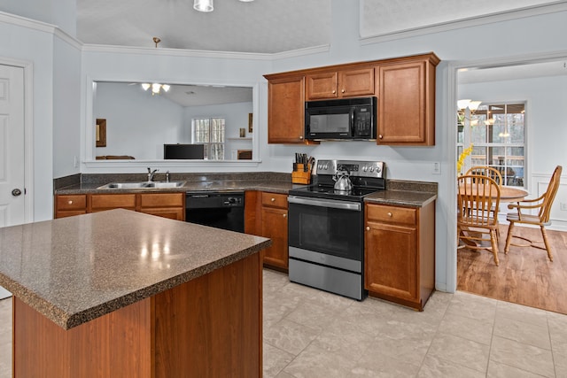 kitchen featuring dark countertops, a healthy amount of sunlight, brown cabinets, black appliances, and a sink