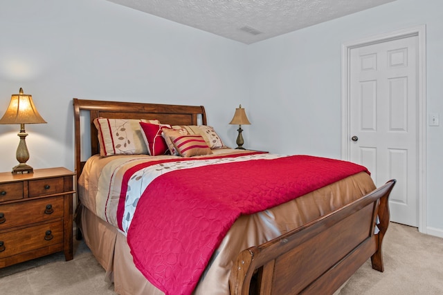 bedroom featuring visible vents, light carpet, and a textured ceiling