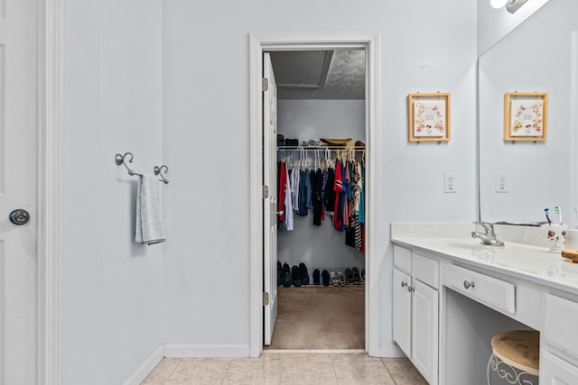 bathroom with vanity, baseboards, a spacious closet, a textured ceiling, and tile patterned floors