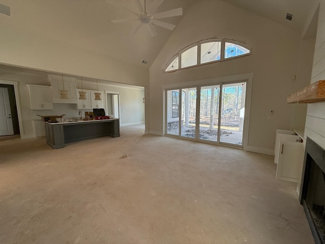 unfurnished living room featuring high vaulted ceiling and ceiling fan