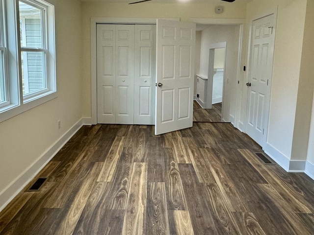 unfurnished bedroom with dark wood-type flooring and a closet