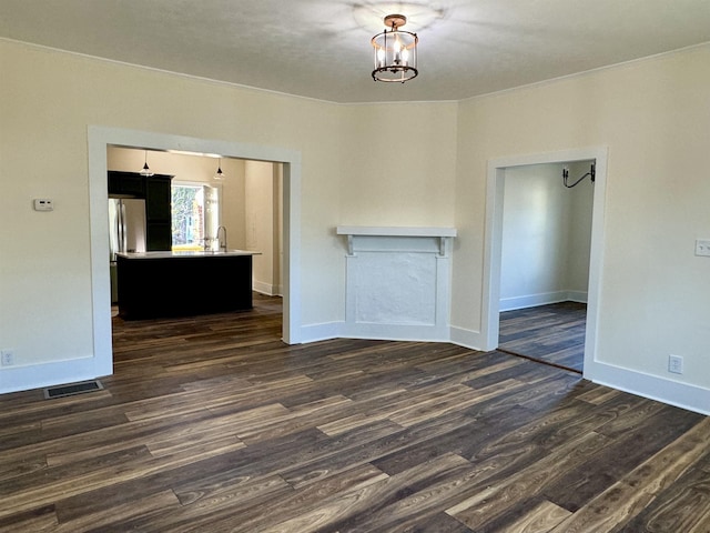 spare room with dark wood-type flooring and a chandelier