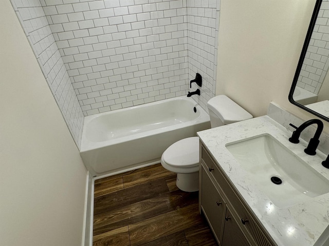 full bathroom with vanity, hardwood / wood-style flooring, toilet, and tiled shower / bath combo