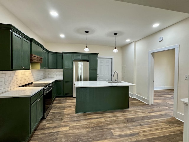 kitchen featuring sink, pendant lighting, stainless steel refrigerator, electric stove, and a kitchen island with sink