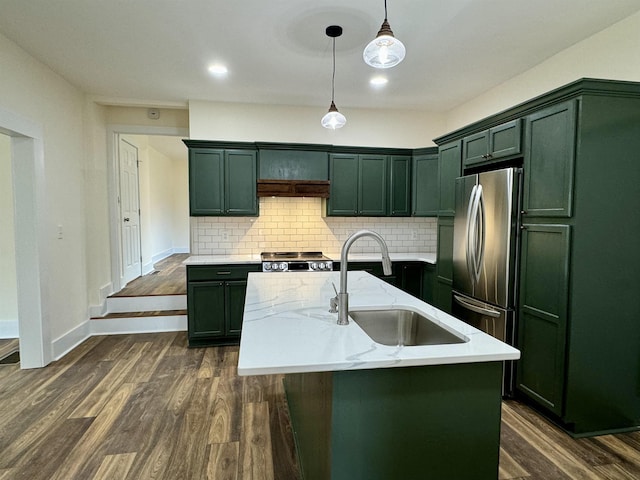 kitchen featuring sink, range, an island with sink, pendant lighting, and light stone countertops