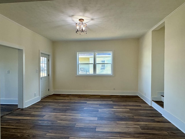 empty room with dark hardwood / wood-style floors and a notable chandelier