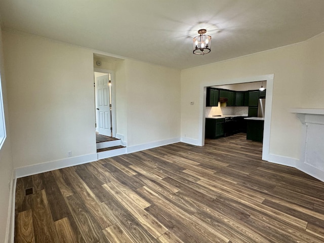 unfurnished living room with dark hardwood / wood-style flooring and an inviting chandelier