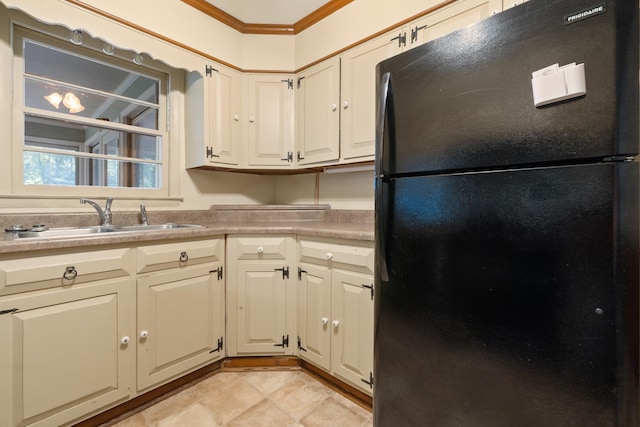 kitchen featuring black fridge, ornamental molding, light tile patterned flooring, and sink