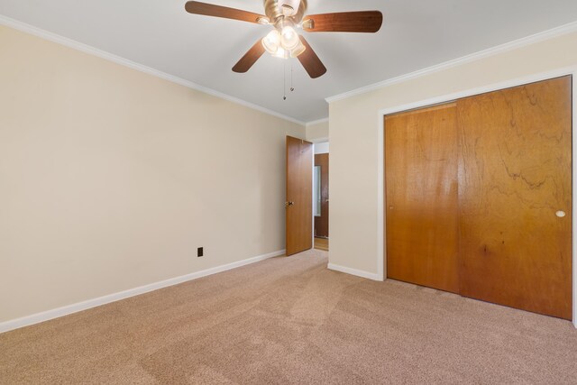 unfurnished bedroom with ornamental molding, light colored carpet, ceiling fan, and a closet