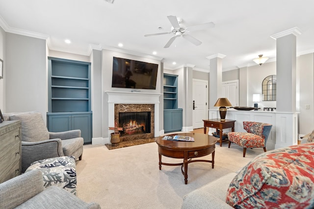 carpeted living room featuring crown molding, a fireplace, built in features, and ornate columns