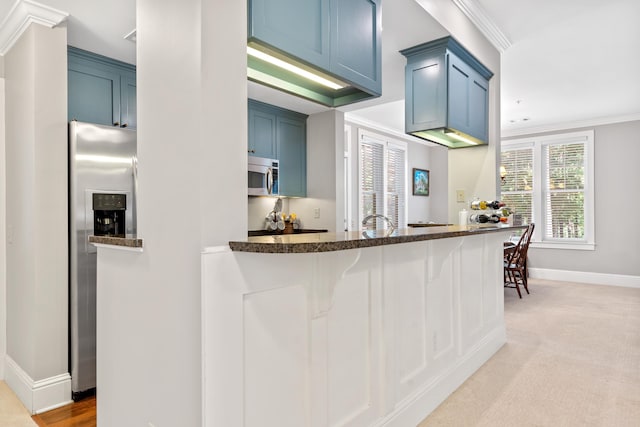 kitchen with crown molding, appliances with stainless steel finishes, blue cabinetry, and kitchen peninsula