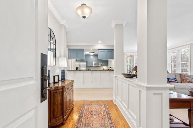 kitchen with ornamental molding, appliances with stainless steel finishes, light hardwood / wood-style floors, and kitchen peninsula