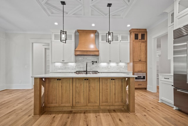 kitchen with appliances with stainless steel finishes, custom range hood, a center island with sink, and white cabinets