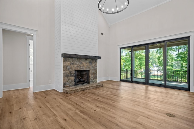 unfurnished living room featuring a fireplace, high vaulted ceiling, a chandelier, and light wood-type flooring