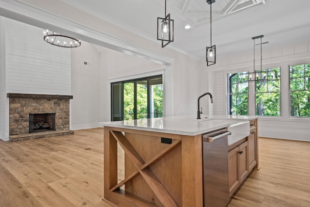 kitchen featuring plenty of natural light, decorative light fixtures, sink, and a center island with sink