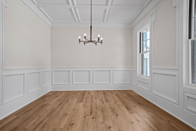 unfurnished dining area featuring coffered ceiling, an inviting chandelier, and light hardwood / wood-style flooring