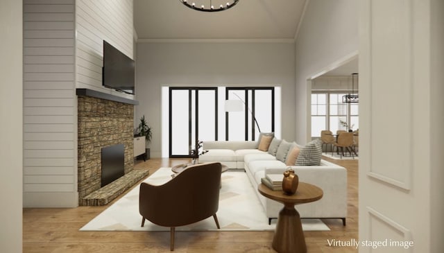 living room with crown molding, an inviting chandelier, a high ceiling, a fireplace, and light hardwood / wood-style floors