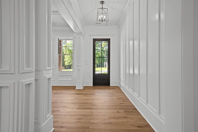 entrance foyer with crown molding, an inviting chandelier, and light wood-type flooring