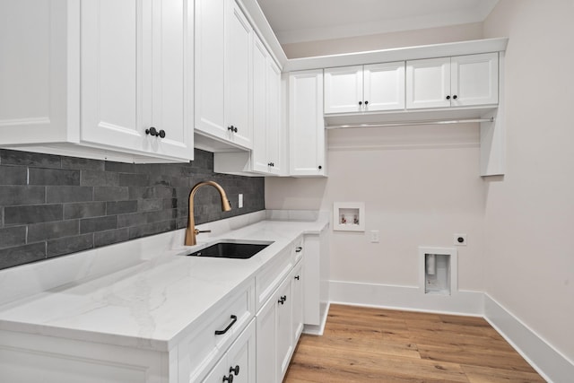 clothes washing area featuring sink, cabinets, light wood-type flooring, washer hookup, and hookup for an electric dryer