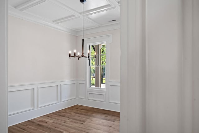 unfurnished dining area featuring coffered ceiling, light hardwood / wood-style flooring, ornamental molding, and a chandelier