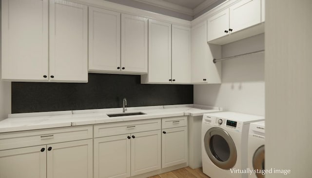 washroom featuring cabinets, sink, washing machine and dryer, and light hardwood / wood-style flooring