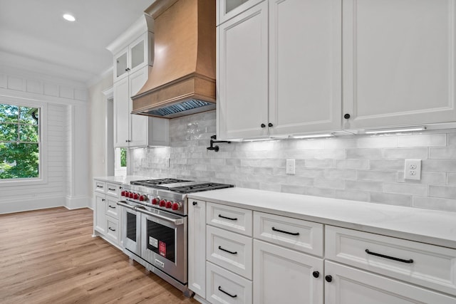 kitchen with white cabinetry, double oven range, tasteful backsplash, custom range hood, and light wood-type flooring