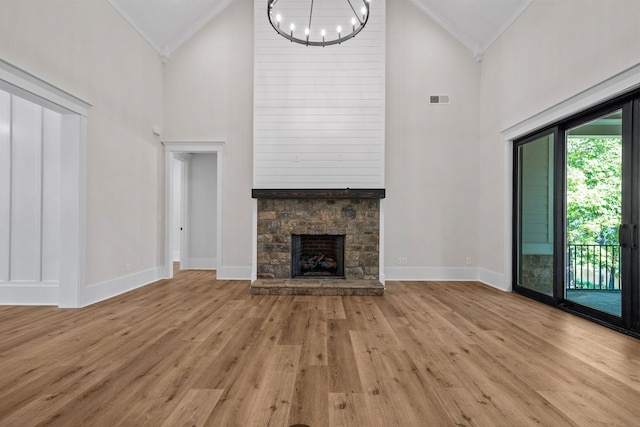 unfurnished living room featuring a chandelier, high vaulted ceiling, ornamental molding, a fireplace, and light hardwood / wood-style floors