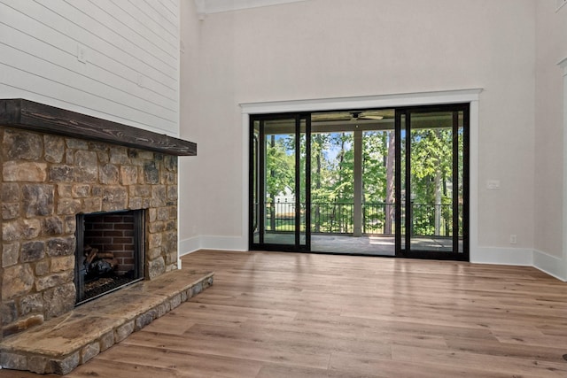 unfurnished living room with a fireplace, light hardwood / wood-style floors, and a high ceiling