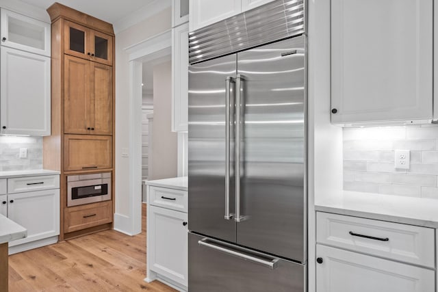 kitchen featuring white cabinetry, built in refrigerator, light hardwood / wood-style floors, and tasteful backsplash