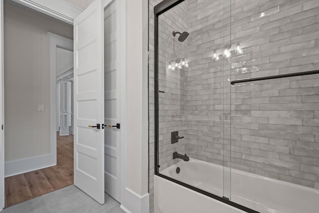 bathroom with hardwood / wood-style floors and bath / shower combo with glass door