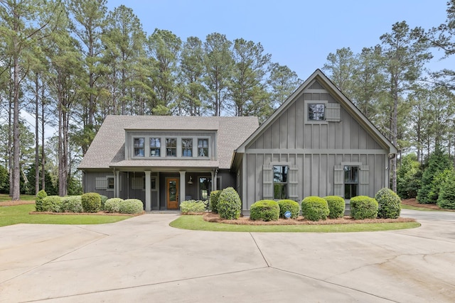 view of front facade featuring board and batten siding, a shingled roof, and covered porch