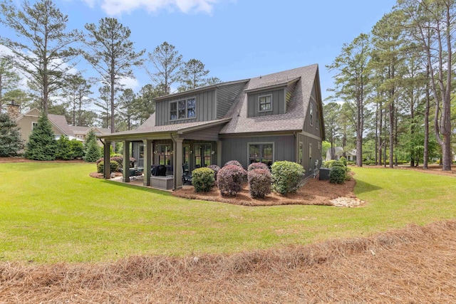 rear view of property featuring a yard, a patio area, and a shingled roof