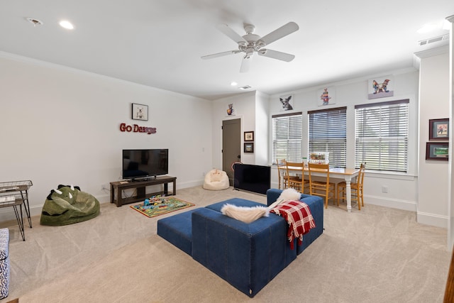 living room featuring light carpet, a ceiling fan, baseboards, and ornamental molding