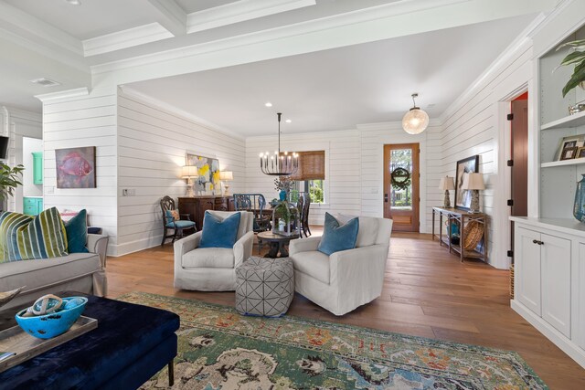 living area featuring wood walls, wood finished floors, a notable chandelier, and ornamental molding