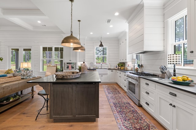 kitchen with white cabinets, tasteful backsplash, dark countertops, high end stove, and a kitchen island