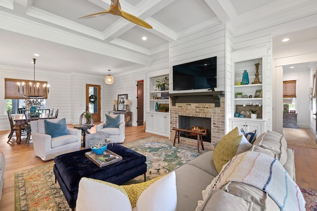 living area with light wood-style flooring, crown molding, and ceiling fan with notable chandelier